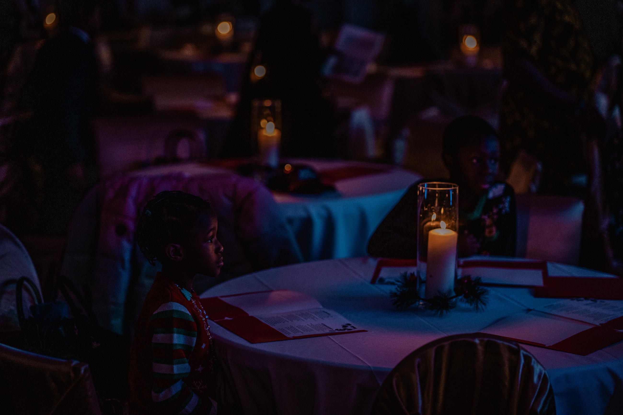 Child seated at a candlelit event